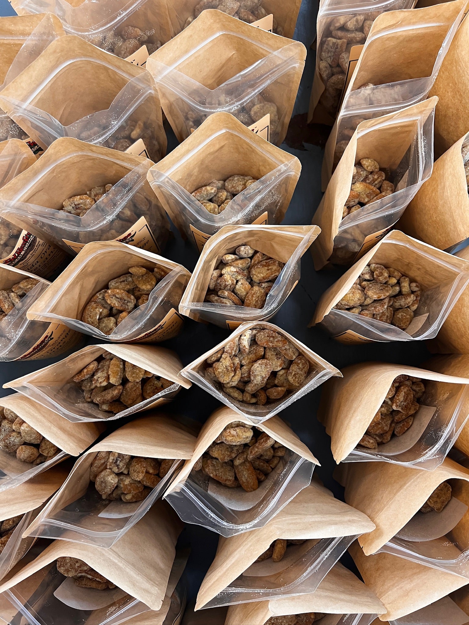 Multiple open bags filled with Renfroe Pecan Company praline pecans viewed from above into inside of bag.
