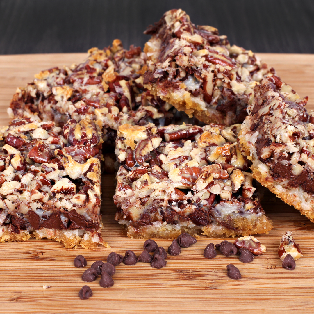 A stack of six layer cookie bars made with chocolate, pecans, and coconut.